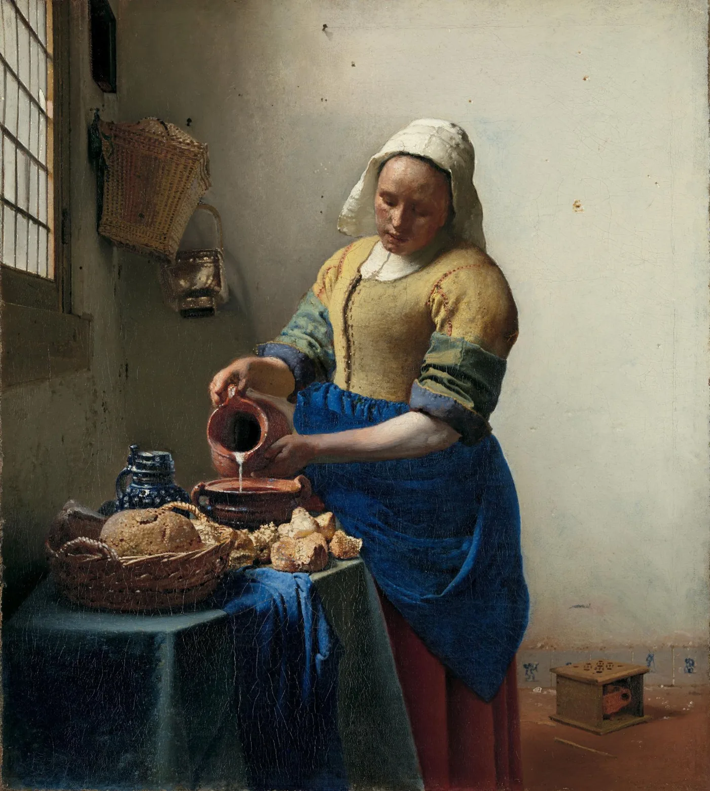 Johannes Vermeer, The Milkmaid: a window divided into small panes at the upper left, a woman pouring milk, and a basket of bread and a white jug on the table.